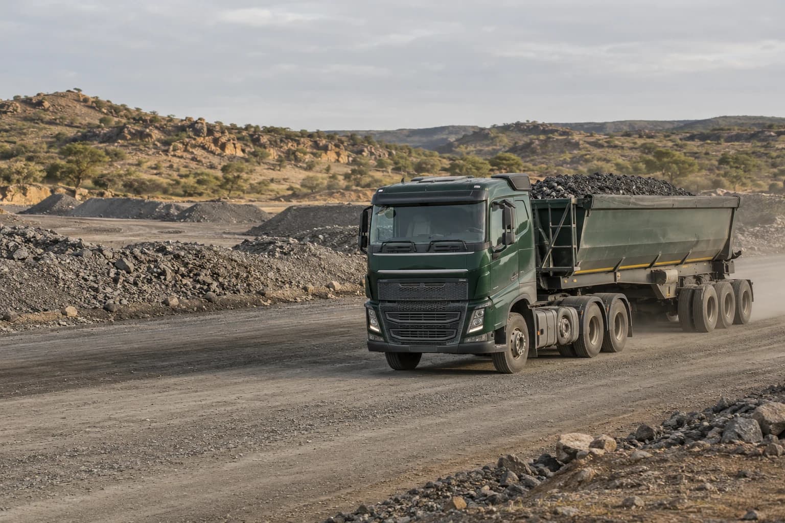 Illustrative mineral haulage truck on a gravel road beside ore stockpiles